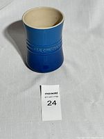 Front view of the blue stoneware utensil jar showing its shape and embossed brand.