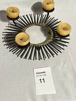 Full view of Mid Century Modern Brutalist candle holder shaped like a ring of nails with four round yellow candles.