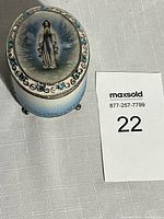 View of the oval porcelain rosary box with Our Lady of Lourdes image and blue rhinestones on lid.