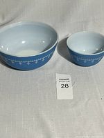 Two Pyrex mixing bowls, one larger and one smaller, blue exterior with white snowflake design