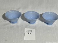 Photo showing three blue custard bowls arranged in a row on a white tablecloth, showing the overall size and shape of each bowl.