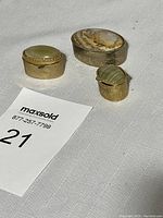 Photo showing all three pill boxes on white textured fabric, noting their metal bases and stone tops
