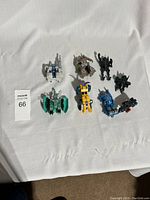 Photo showing all 8 miniature Transformers figurines on white fabric background, displaying variety of characters and colors