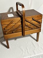 Closed view of the vintage wooden sewing box showing the accordion hinges and handle.