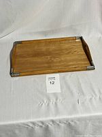 Full view of the rectangular wooden serving tray on white fabric background, showing cutout handles and metal corner accents.