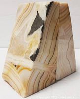 View of one stone bookend showing natural banded pattern in beige, brown, black and white colors