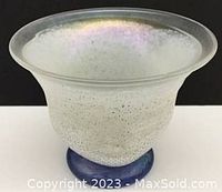 Front angled view of the iridescent vase showing its flared rim, white textured body, and blue base.