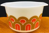 Front view of vintage Pyrex mixing bowl with orange and brown arches fish scales pattern on white glass.