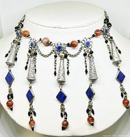 Front view of the Tibetan silver-toned beaded choker displaying engraved silver cones, blue lapis lazuli stones, round orange carnelian beads, and black bead details against a white bust form.