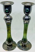 Pair of two candlestick holders with green glass stems and silver tops featuring green gem-like accents. Show the front and side views together to illustrate the pair and design.