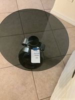 Top view showing round tinted glass top with metal base underneath.