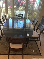 Top view showing the smoked glass rectangular dining table surrounded by six matching chairs with slatted backs and cream seats.
