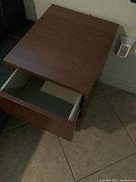 Pair of medium brown wood two-drawer nightstands seen from top corner angle showing open drawer.