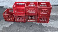Front view of all 7 red plastic milk crates stacked in two rows highlighting brand labels Silverwood and Sealtest