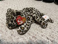 Ty Beanie Baby Freckles leopard plush lying on carpet showing the attached TY heart-shaped tag and tail tags.