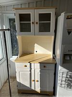 Full front view of the wood kitchen cabinet showing upper glass doors, countertop, central drawer, and lower doors.