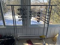 Front view of chrome metal clothing rack with hanging tiered clip hangers and wire hangers.