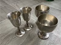 Full view of all four pewter goblets, two tall stemmed and two shorter round ones, showing finish and shape