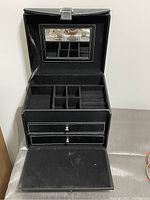 Interior view of the jewelry box with lid open showing mirror, multiple compartments, ring cushions, and two drawers.