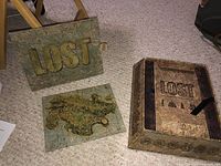 Collector's box set with Lost logo and island map on carpeted floor.
