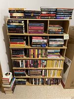 Full view of multiple shelves filled with over 145 hardcover and softcover books stacked and arranged in groups by author and series