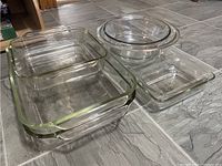 Photo showing a group of clear glass Pyrex bakeware dishes of mixed sizes and shapes on tiled floor.