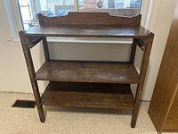 Front view of vintage wooden shelf showing three shelves and scalloped back panel on top shelf.