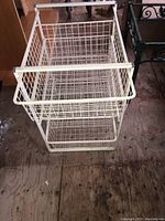 Overall image of the white wire storage shelving unit showing structural frame and five pull-out baskets.