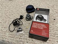 Two Motorola wireless Bluetooth headsets shown on carpet with original retail packaging, charging case, wired earphones and accessories.