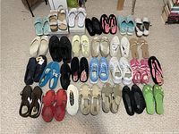 Overview showing approximately 30 pairs of women's shoes arranged on floor, mostly size 9-10 with some size 11.