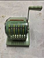 Front angled view of antique heavy cheque printer showing dollar and cent selector dials with white toggles and dollar signs.