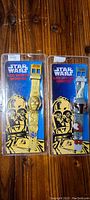 Front view of two sealed Star Wars LCD watches featuring C-3PO and R2-D2 in original packaging, showing watch bands and packaging art.