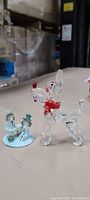Photo of glass dog ornament and porcelain snowman couple on a table with warehouse background.