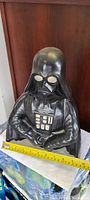 Front view of vintage Darth Vader figure with measuring tape showing width around 10 inches