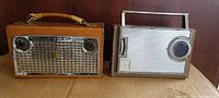 Front and side view of both vintage Zenith portable transistor radios displayed side by side on a wooden shelf.