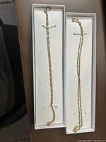 Two yellow gold rope chain necklaces displayed in white presentation trays