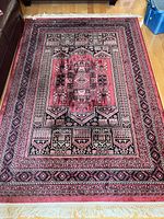 Full view of red, black and beige geometric pattern area rug laid on wood floor