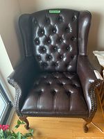 Front view showing tufted button detail on back and seat, wingback silhouette and wood legs