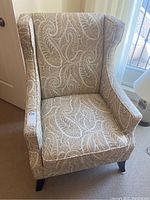 Front view of modern armchair showing detailed paisley upholstery and wingback design