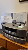 Front view of main Wave unit stacked on CD changer module with power cord on top and original box in background