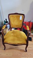 Front view of the Queen Ann style armchair showing mustard yellow cushioned velvet upholstery and carved wood frame.