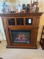 Front view of fireplace cabinet with insert powered on and decorative items on mantle