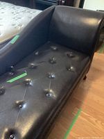 Leatherette fainting couch showing tufted seat and backrest with button detailing and the single raised armrest.
