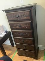 Front view showing six drawers with carved floral detailing and round knobs