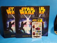 Three Star Wars Episode III Revenge of the Sith poster books displayed upright, showing cover art with characters fighting with lightsabers in a blue and black tone.