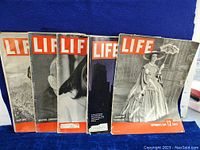 Five vintage Life magazines arranged in a line showing covers with various subjects like a woman in period costume and black and white portraits. Covers show wear and tear consistent with vintage condition.