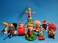 Photo of all nine assorted 1980s animated figures and toys including Grinch, California Raisins, troll, and others on blue background