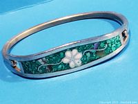 Bracelet showing entire band, silver, turquoise chip inlay, and floral abalone design
