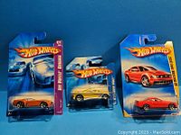 Three Hot Wheels Mustang model cars in original blue packaging, displayed together.
