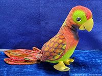 Side profile of colorful vintage parrot plush stuffed animal showing overall shape, fabric colors, and plastic feet.
